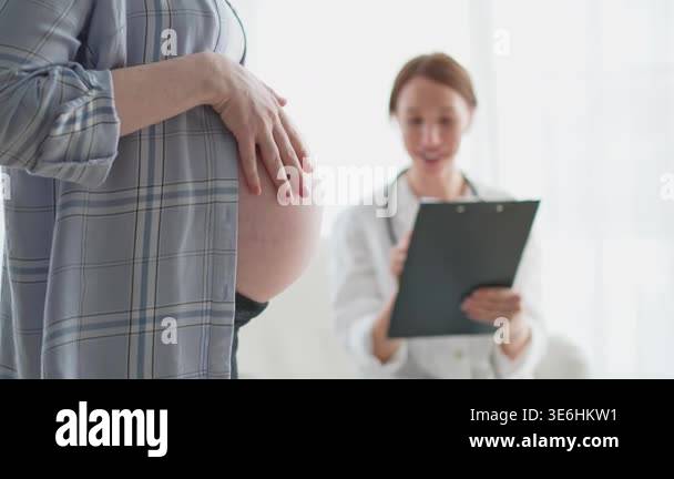 Pregnant woman hands touching big belly in doctor office. Female doctor ...