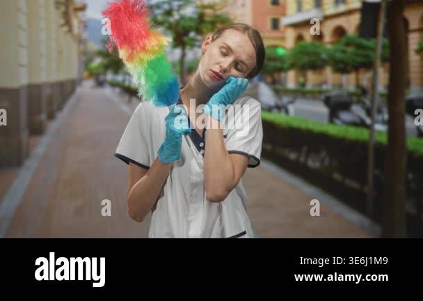 Cleaning woman in uniform holds rainbow feather duster, gloved hand ...