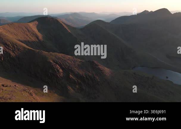 Dramatic highaltitude ridges glowing in warm sunset light above a ...