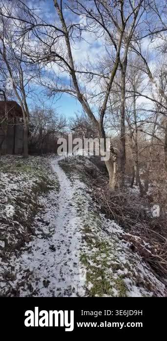 Cinematic slow-motion POV walking along a narrow path by a winter river ...