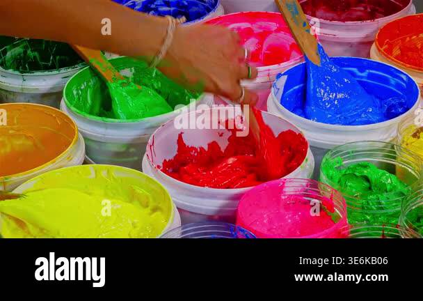 Person mixing bright red paint in a container surrounded by various ...