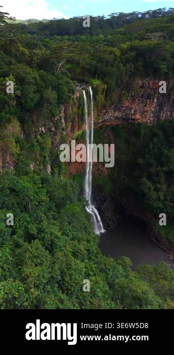 Aerial view of majestic waterfall cascading down lush, green cliffside ...