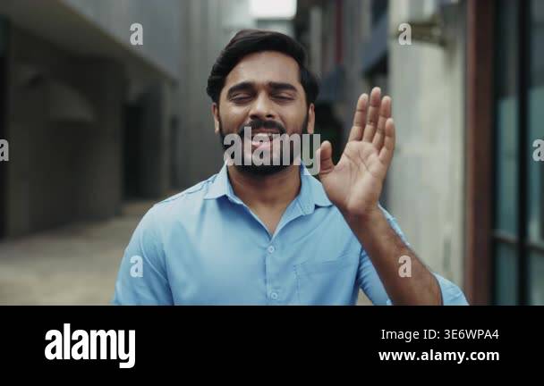 Portrait of happy Indian man in blue shirt using sign language on old ...