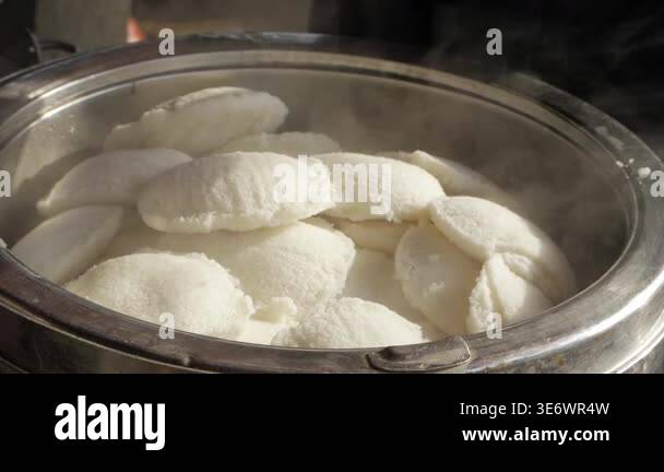 Soft white dumplings steaming in a metal container on a food stall ...