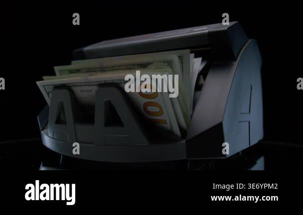 Side view of a cash counting machine processing US hundred dollar bills ...