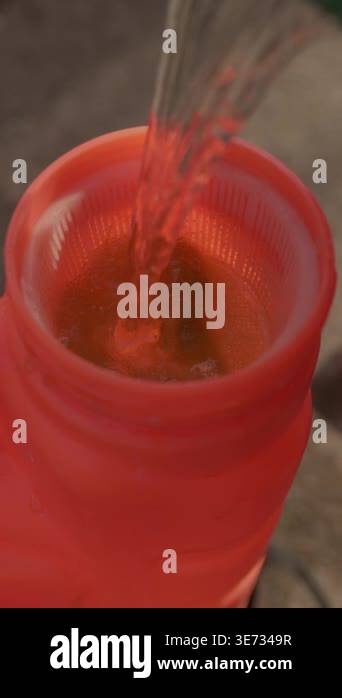 Vertical video. Close-up of a gardener pouring water into an orange ...