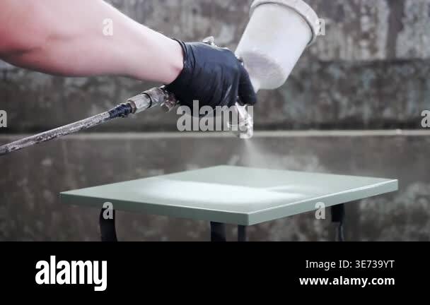 Worker applying paint with spray gun on panel surface in industrial ...