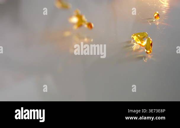 Golden softgel capsules falling on table in warm light concept of ...