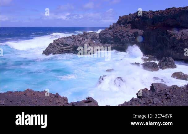 Powerful ocean waves crashing against rugged volcanic cliffs, creating ...