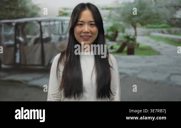 Young chinese woman smiling and saluting in a green park setting with ...