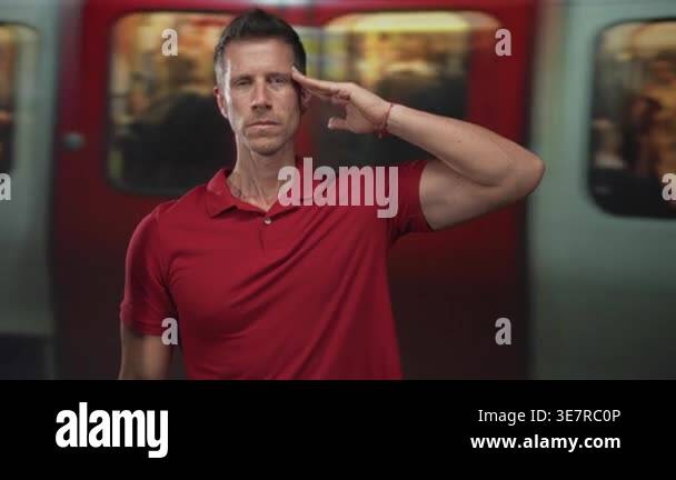 Man saluting with hand to temple at train station platform, eyes closed ...