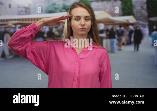 Woman in pink shirt saluting at market street with background blurred ...