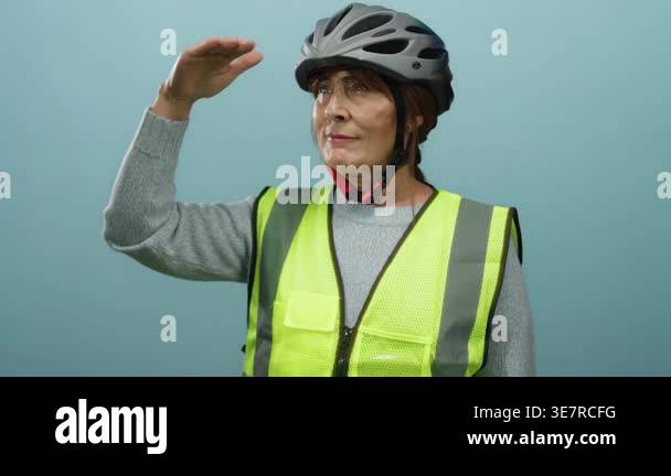 Senior hispanic woman with helmet and safety vest saluting while ...