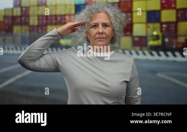 Woman saluting at a port with a backdrop of colorful shipping ...