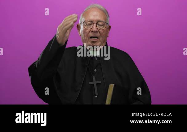 Senior priest in black robe, holding a book, stands over an isolated ...