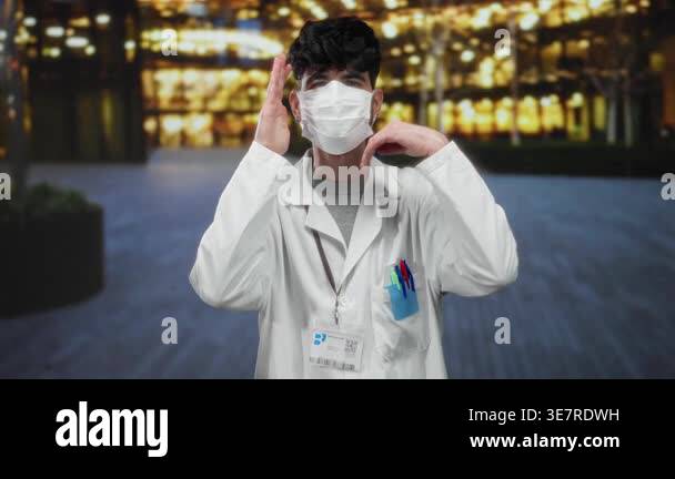 Young man wearing mask and lab coat adjusting his glasses outdoors in ...
