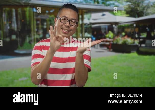 Man making ok sign with right hand and pointing at open left palm on ...