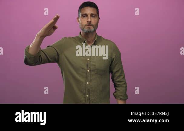 Man saluting with raised hand and visible forearm in pink studio ...