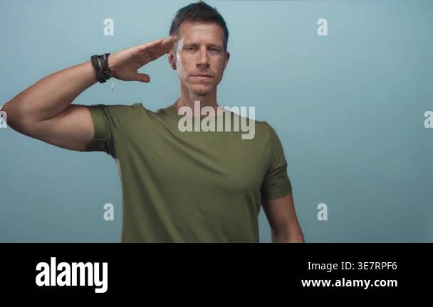 Man saluting with visible forearm and hand in studio against light blue ...