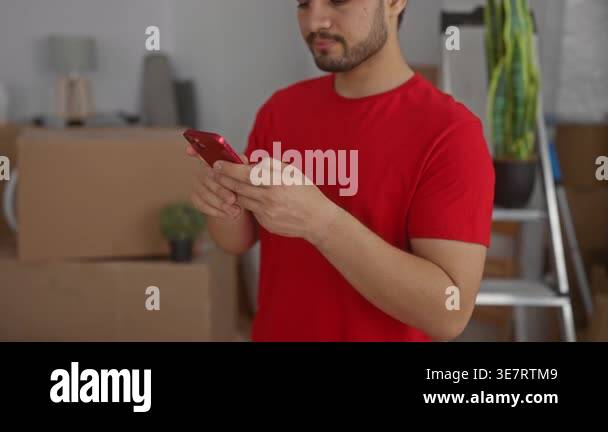 Young hispanic courier man in red cap taps smartphone with hands in a ...