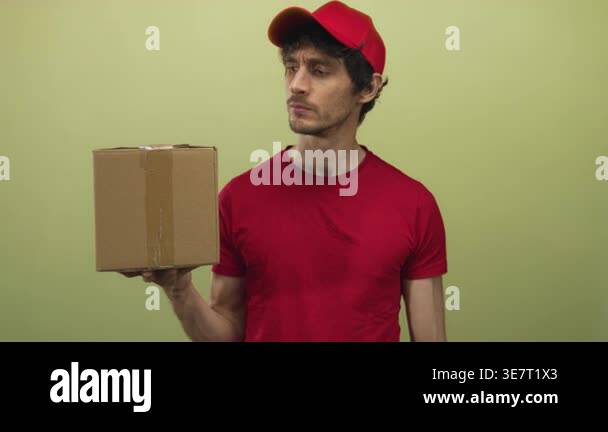 Man wearing red cap and shirt holding box and checking package while ...