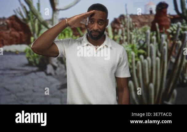 Man saluting with hand to forehead in park among cactus plants and ...
