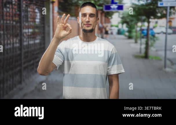 Man making ok sign with right hand on an urban street standing on the ...