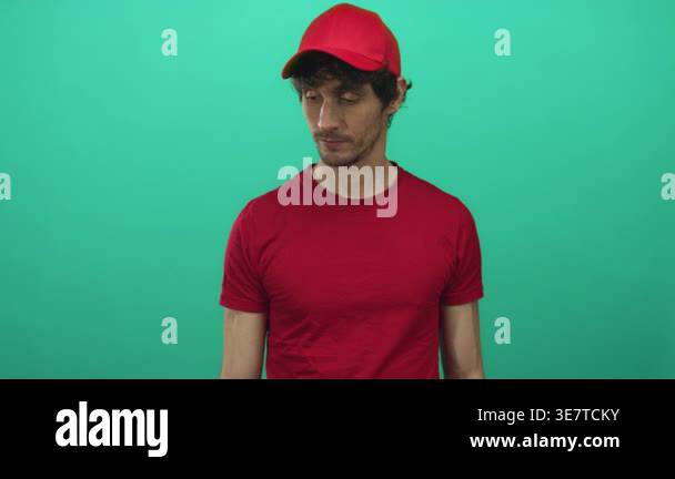 Young delivery man wearing red cap and red shirt looking downward ...