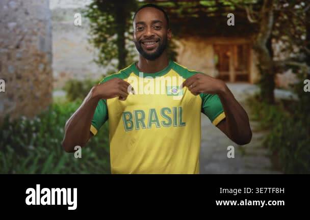 Man points to brasil jersey and flag patch with both hands at building ...