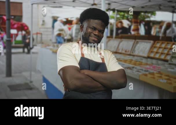 Man with arms crossed and smiling in an apron at a street market ...