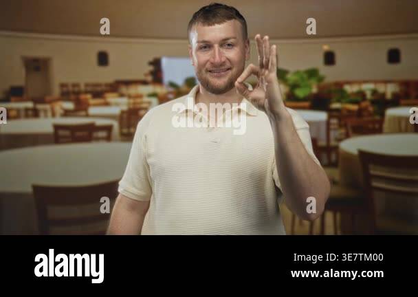Young caucasian man making ok sign with right hand and smiling in an ...