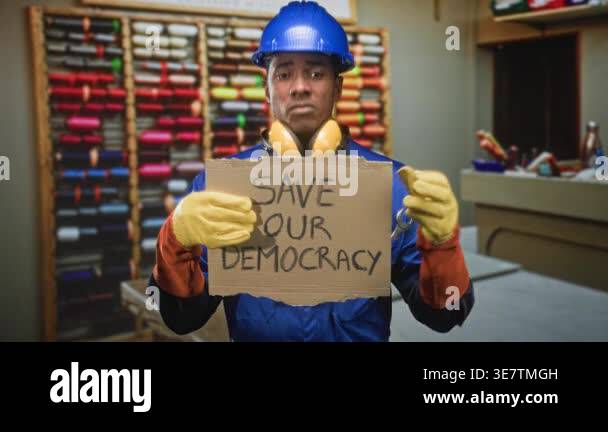 Man in hardhat and coveralls holding a cardboard sign reading save our ...