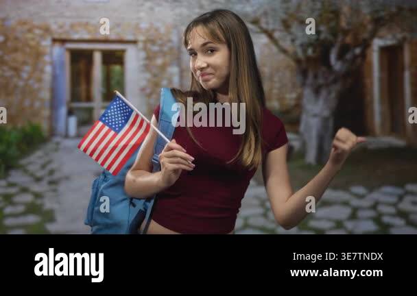 Woman holding american flag and points thumb to building entrance while ...