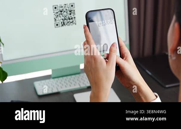 Person scanning QR code from computer screen with smartphone at home ...