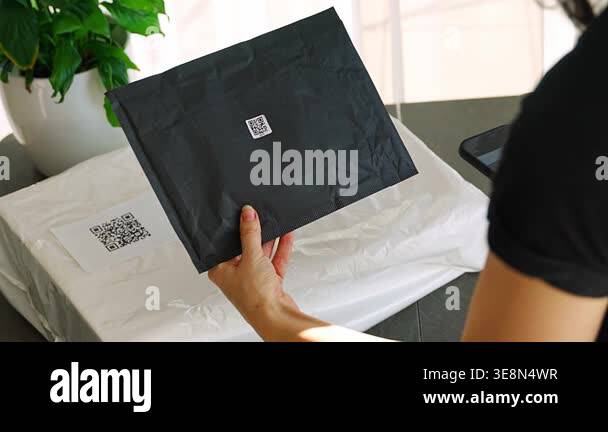 Person scanning QR code on parcel with smartphone camera with focus on ...