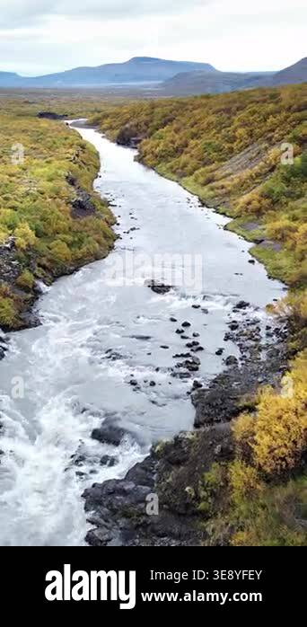 Aerial drone view of a winding river flowing through a remote Icelandic ...