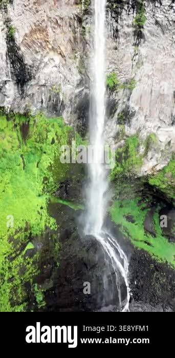 Aerial drone view of multiple waterfalls cascading down a lush green ...