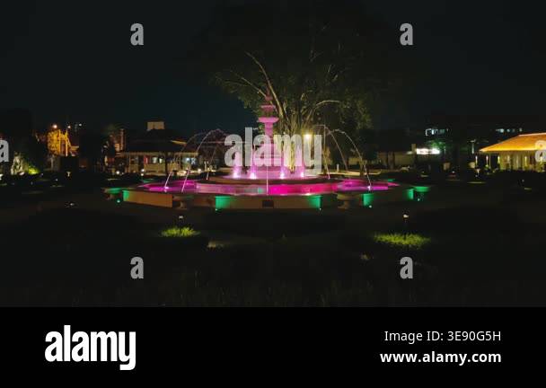 A beautiful water fountain in a public park is illuminated with ...