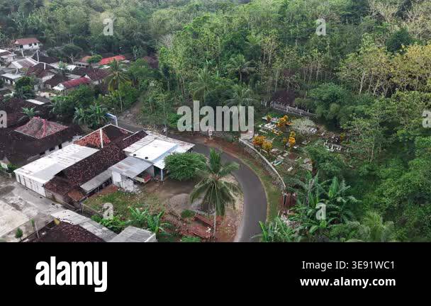 Aerial drone footage of a rural village surrounded by lush greenery and ...