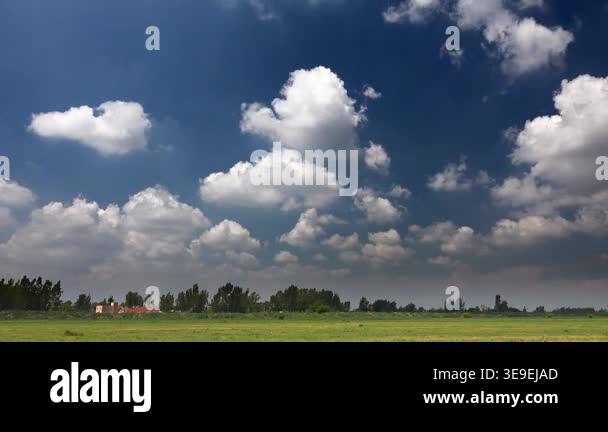 Time lapse video of partly cloudy blue sky over flat plain farmland and ...