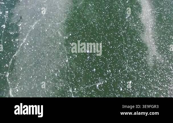 Aerial view of frozen lake surface with thick ice layer and cracks in a ...