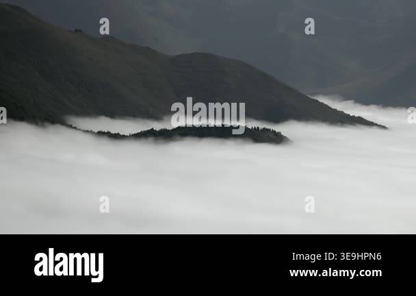 Caucasus mountain ridge above sea of clouds, green slopes in misty ...