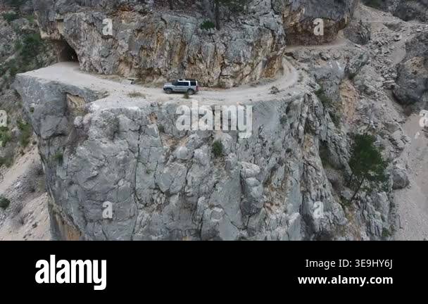 Aerial view of car driving along extremely dangerous rocky mountain ...