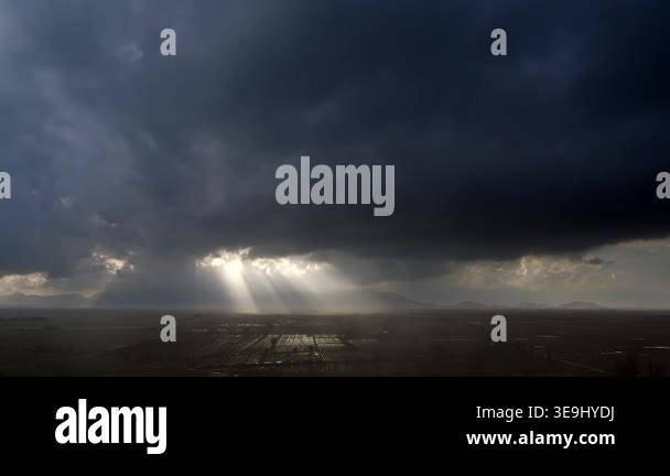 Sun rays breaking through dense storm clouds before and after rain over ...