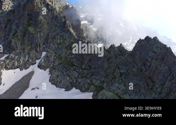 Aerial timelapse of sharp rocky alpine mountain peaks in summer across ...