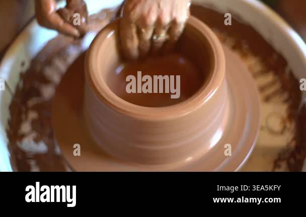 A ceramics artist shapes wet clay on a spinning potters wheel during ...