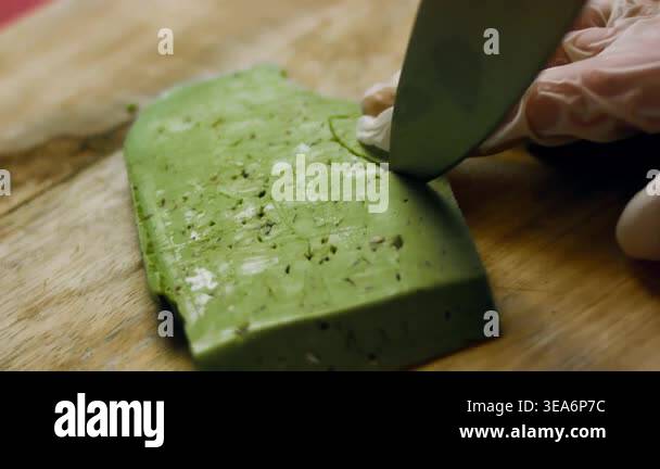Close up of a person cutting pesto cheese into pineapple leaf patterns ...