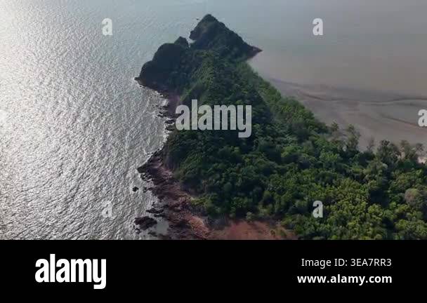 Aerial view of lush green cliffs meeting calm waters. Waves lap gently ...