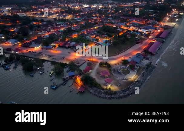 Aerial night view of coastal town by water. Boats dot calm river ...