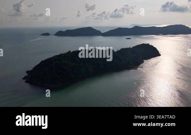 Serene islands rise from calm ocean waters. Sunlight glints off gentle ...